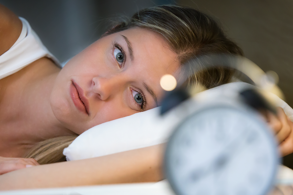 woman unable to sleep staring at clock
