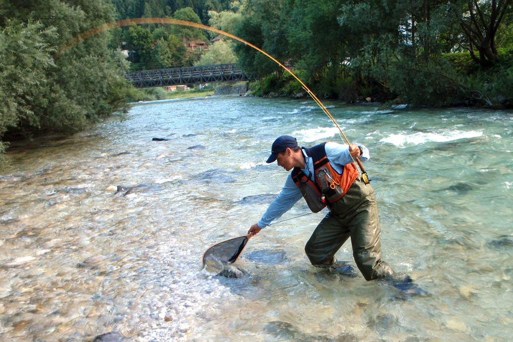 man fly fishing in a river