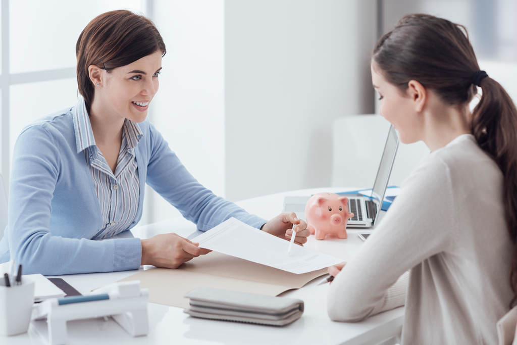 Two women discuss paperwork in an office setting