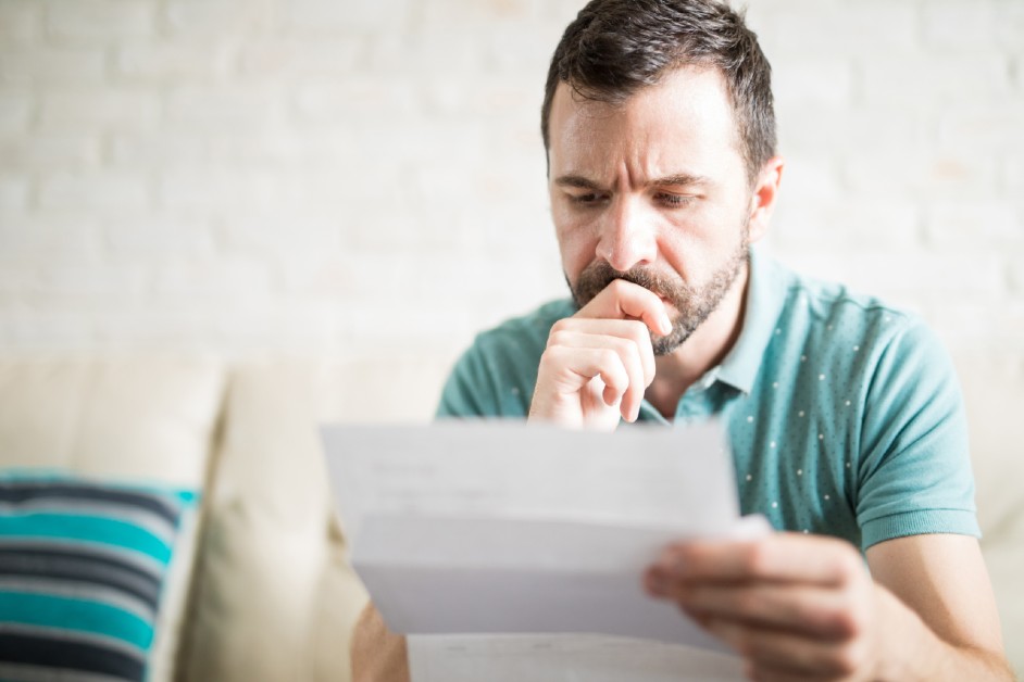A middle aged man thoughtfully looking at his claim paper