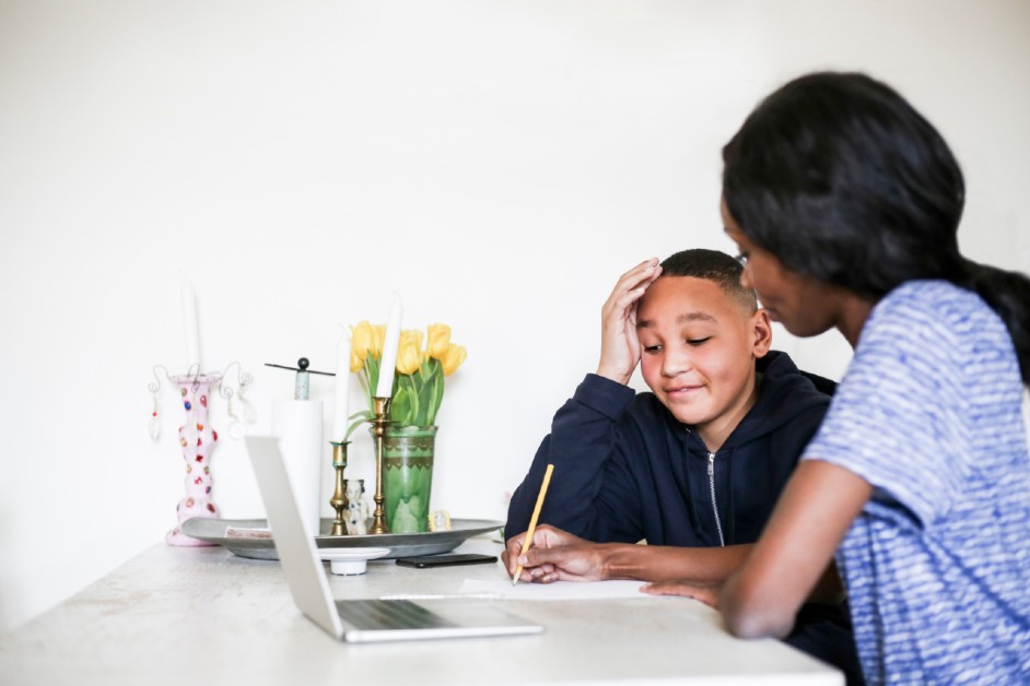 A black mother helping her son with school work