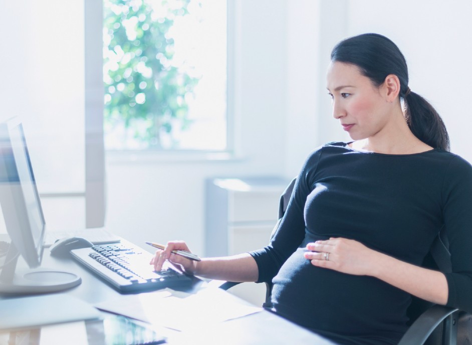 A pregnant employee working on her computer