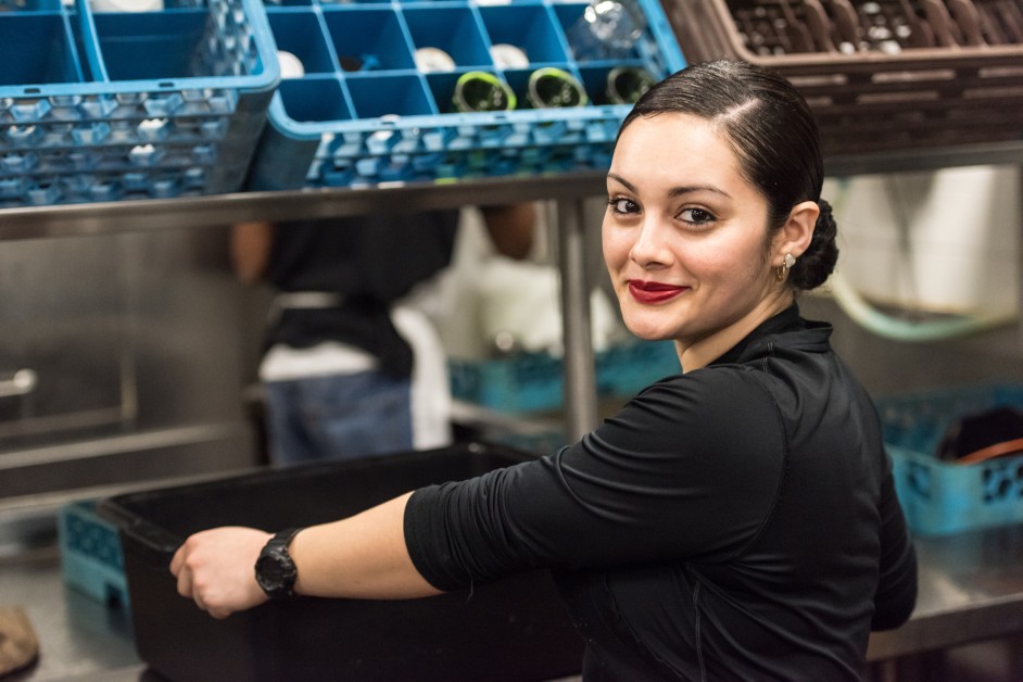 A young female employee working in the back of a store, smiling at the camera