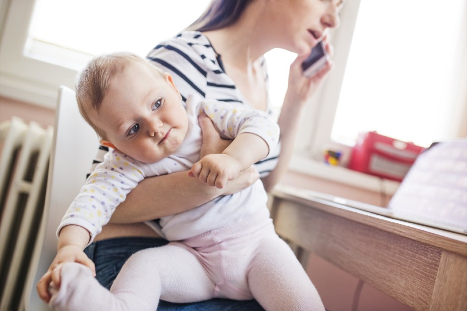 Woman trying to work with baby on lap