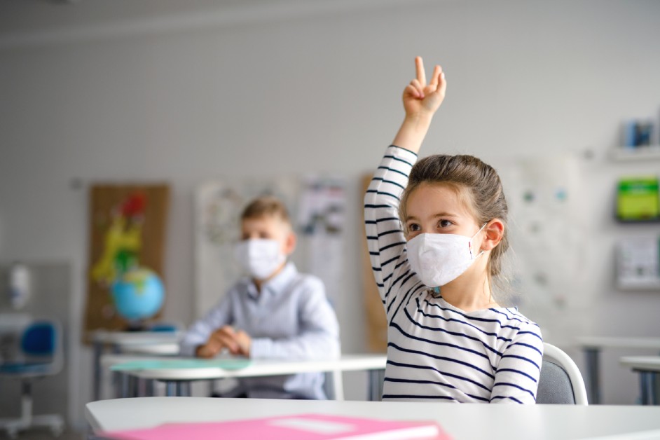 student raising hand in classroom during a pandemic