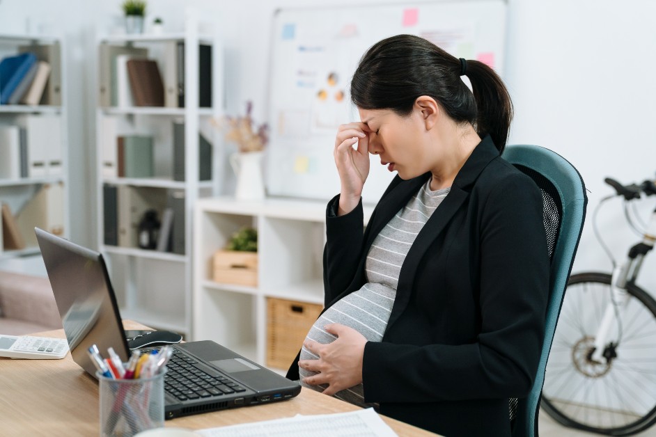 Pregnant woman at desk looking upset