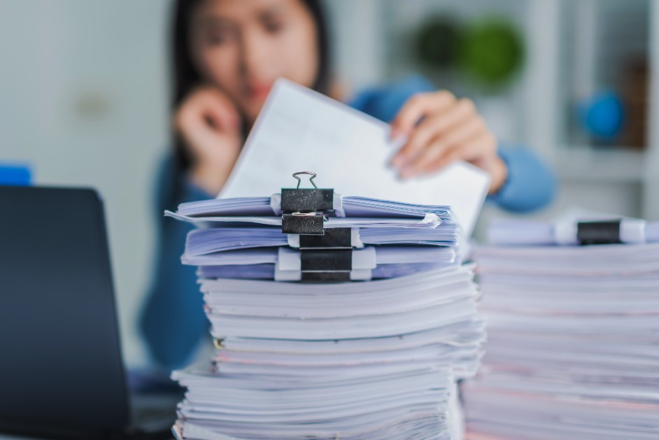 Woman sitting at desk with a pile of paperwork