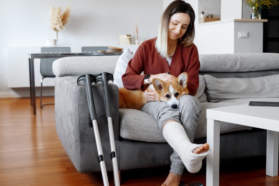 Woman with injured leg at home with dog