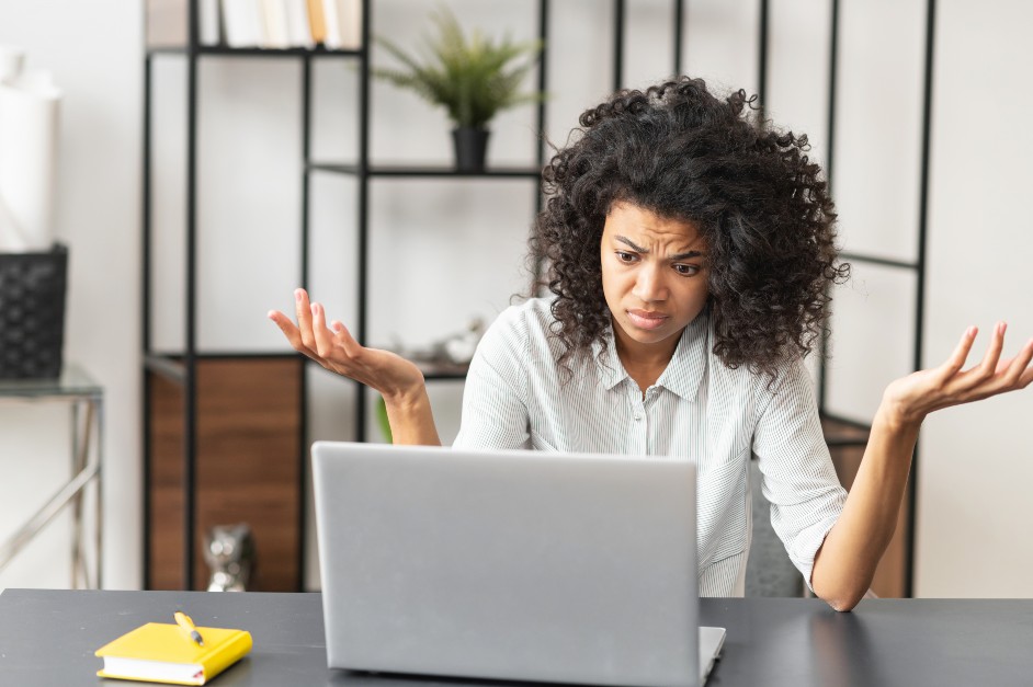 Woman sitting at laptop looking confused