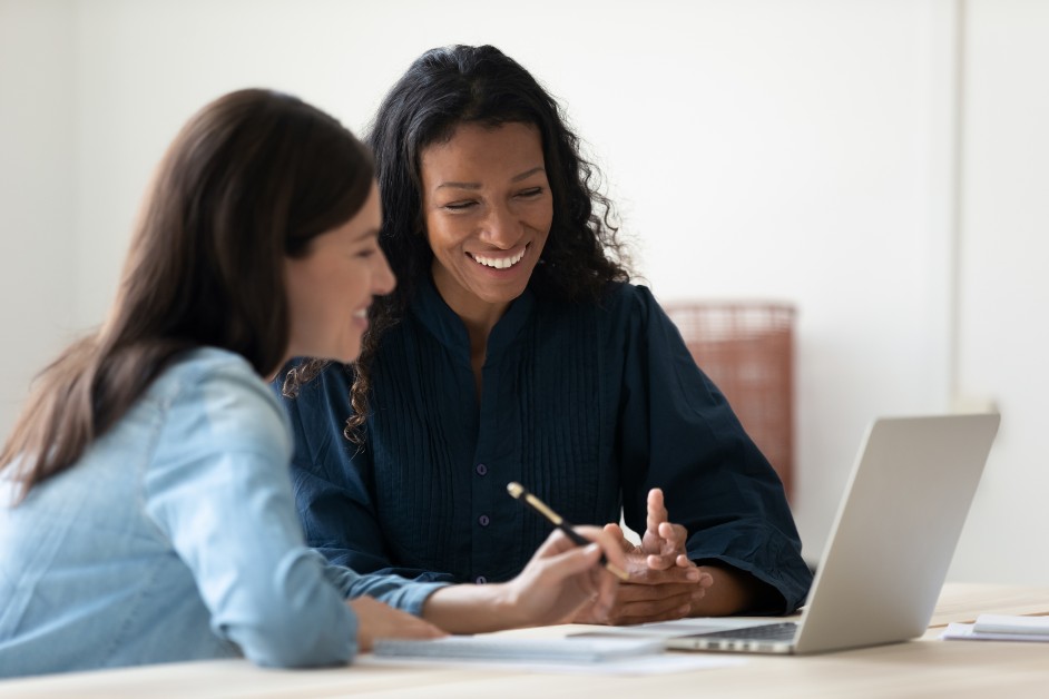 Two women looking at laptop during discussion and smiling